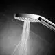 Brausekopf der Marke Ideal Standard, mit einem Wasserstrahl aus mehreren Düsen, montiert an einer flexiblen Halterung, vor einer dunklen Fliesenoberfläche.
